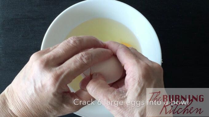 cracking an egg into large white bowl 