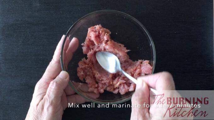 mixing minced pork and light soy sauce with teaspoon in glass bowl