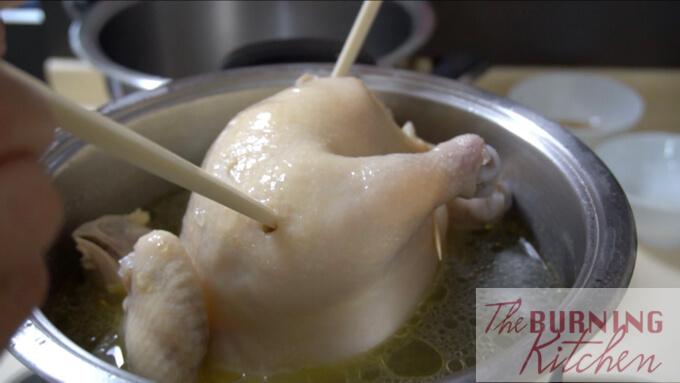 sticking a chopstick into the hainan chicken to see if it is cooked