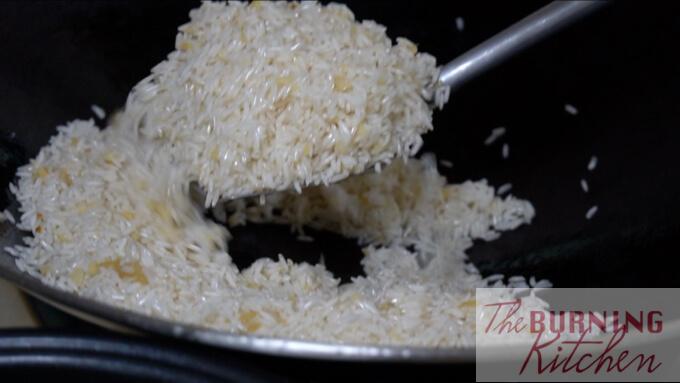 stir frying rice and grated ginger and grated garlic in a wok with chicken fat