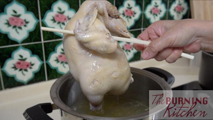 lifting the hainan chicken out of the boiling water with chopsticks