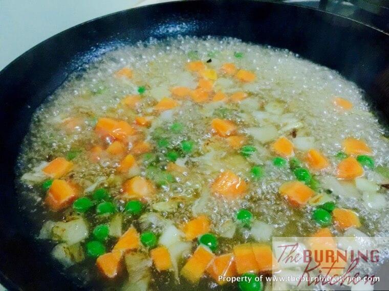 Stir-frying diced carrots, onions and peas and sauce in pan