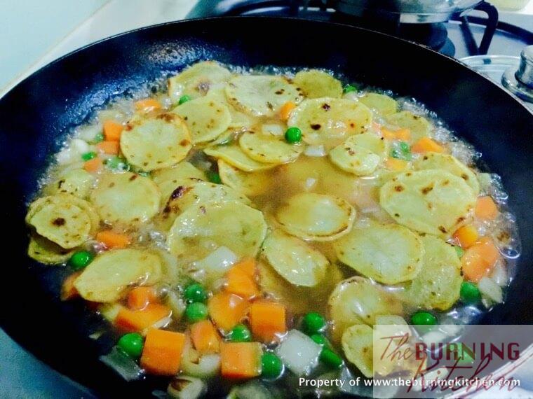 Stir-frying diced carrots, onions, peas, sauce and potatoes in pan