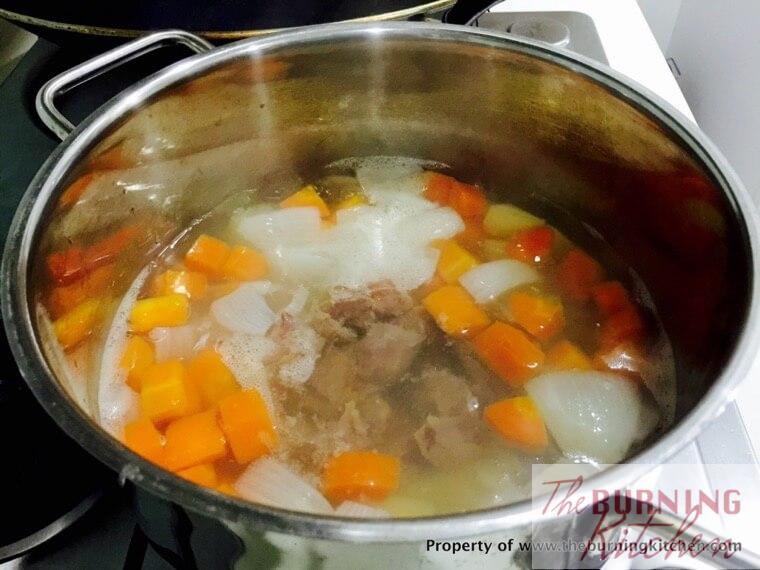 lean pork meat, carrots and potatoes boiling in water in metal pot