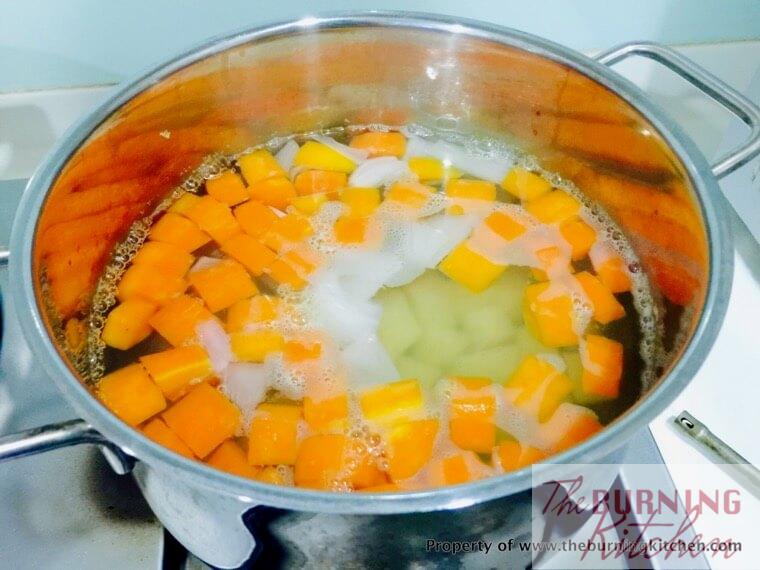 Carrots and potatoes in metal pot boiling in hot water on stove