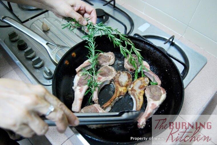 Pan frying lamb cutlets with rosemary sprigs in pan