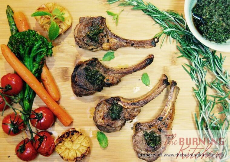 Rosemary lamb cutlets on a wooden chopping board with rosemary sprigs and roasted vegetables