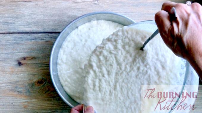 Transferring bowl of grated tapioca mixture to baking tin