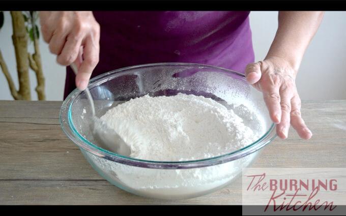 Sifting white flour in glass bowl