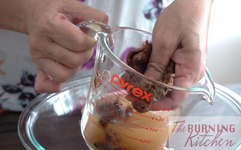 Squeezing tamarind water out of tamarind pulp into measuring cup