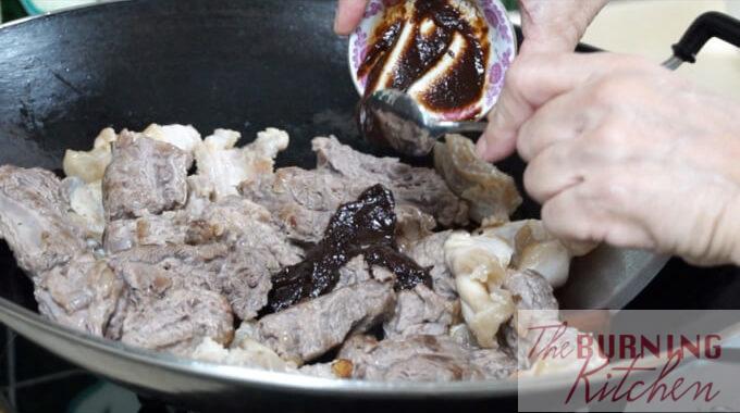 Zhu Hou sauce being added to the wok of beef brisket and beef tendon
