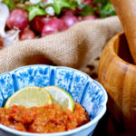 Sambal Terasi in a blue patterned bowl with slices of lime