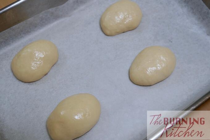 slightly oily dough balls on baking paper in baking tray 
